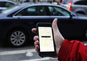 a hand holding a cellphone in front of a car